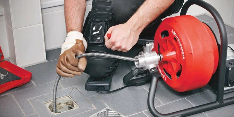 Plumber using a drain-cleaning machine in Windsor