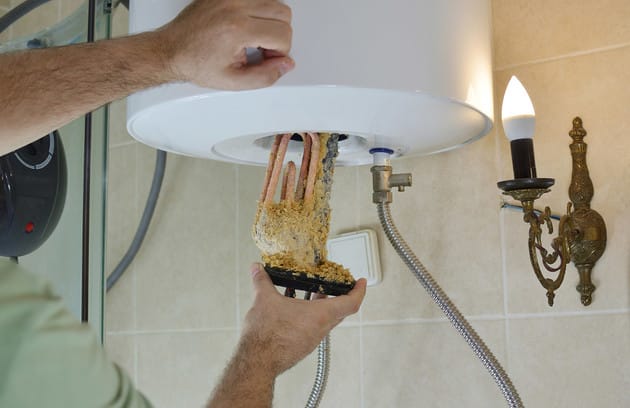 Technician removing mineral buildup from a water heater in Windsor