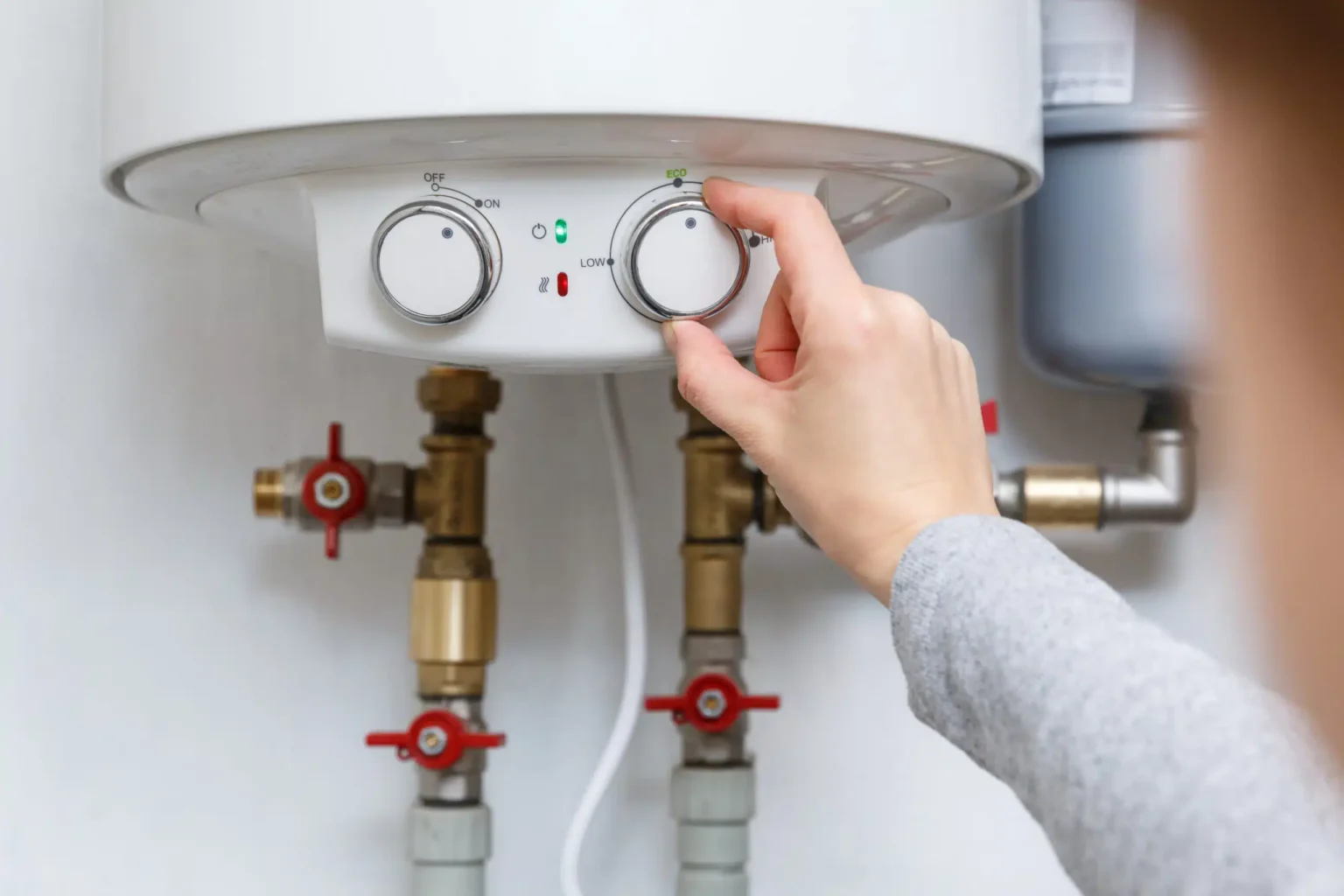 Homeowner adjusting the temperature controls on a water heater in Windsor